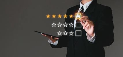 Businessman touching virtual screen on satisfaction rating icon in customer service and satisfaction concept. to give a good rating on the service That rating is a star icon. photo