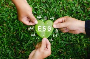 concepto de icono de esg, trabajo en equipo, participación en la protección del medio ambiente en forma de corazón y en negocios sostenibles en la conexión de red sobre fondo verde. foto