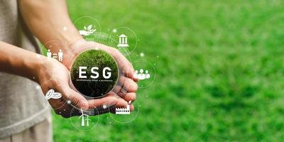The hand that holds the world ready to use the technology of renewable resources to reduce pollution. In concept icon ESG in hand for the environment, society and sustainable business governance. photo