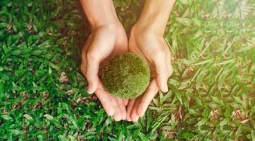 Young woman hand holding the earth on green background. Top view. Protecting nature. Save the earth. Environmental concept. earth day