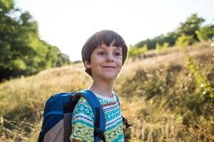 A boy with a backpack walks in the meadow photo