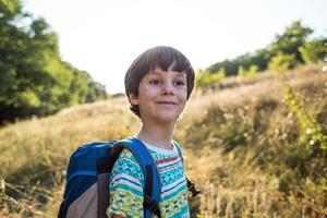 un niño con una mochila camina en el prado foto