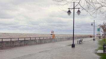 vagues se brisant sur le mur du phare sur le lac michigan à kenosha, mur de pierre avec des nuages lors d'une tempête de force coup de vent le long de la côte du wisconsin causant des inondations et des dommages aux ports et marinas