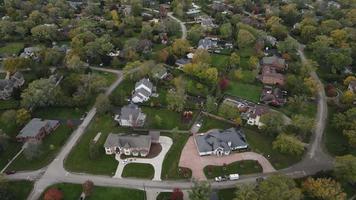 Aerial view of residential neighborhood in Northfield, IL. Lots of trees starting to turn autumn colors. Large residential homes, some with solar panels. Meandering streets