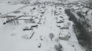 neve caindo sobre a vizinhança rural no vale em Wisconsin. casas unifamiliares em cada lado da rua coberta de neve. estrada que separa a fazenda das casas. nova construção de casas. video