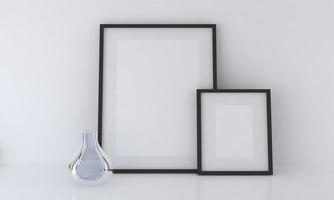 Representación 3D de maquetas de marcos en blanco junto a un jarrón de vidrio apoyado contra una pared blanca foto
