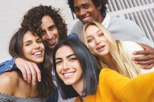 Grupo multiétnico de amigos tomando un selfie juntos mientras se divierten al aire libre. foto