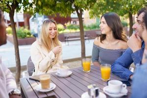 Multi-ethnic group of friends having a drink together in an outdoor bar. photo