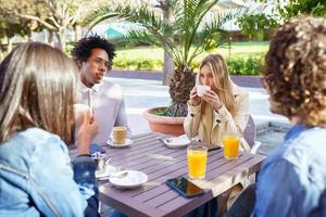 Grupo multiétnico de amigos tomando una copa juntos en un bar al aire libre.
