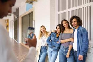 Grupo multiétnico de amigos tomando fotos con un teléfono inteligente en la calle.