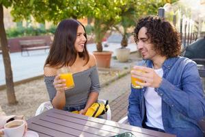 Couple of friends toasting while having a drink with their multi-ethnic group of friends photo