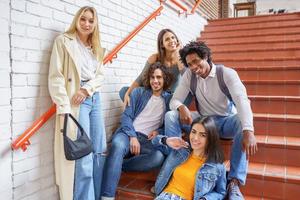 Group of friends with ethnic variety, sitting on some street steps having fun together. photo