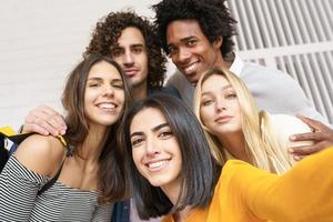Grupo multiétnico de amigos tomando un selfie juntos mientras se divierten al aire libre. foto