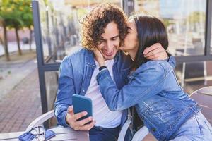 Arab couple looking at pictures taken with their smartphone outdoors photo