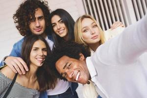 Grupo multiétnico de amigos tomando un selfie juntos mientras se divierten al aire libre. foto
