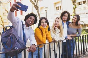 Black man with afro hair taking a smartphone selfie with his multi-ethnic group of friends. photo