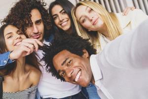 Grupo multiétnico de amigos tomando un selfie juntos mientras se divierten al aire libre. foto