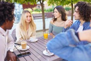 Multi-ethnic group of friends having a drink together in an outdoor bar. photo