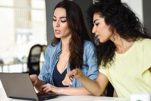 dos mujeres jóvenes que estudian con una computadora portátil.
