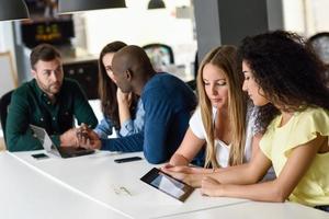 Grupo multiétnico de jóvenes que estudian con ordenador portátil foto