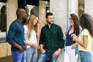 Grupo multiétnico de amigos divirtiéndose juntos en el fondo urbano foto