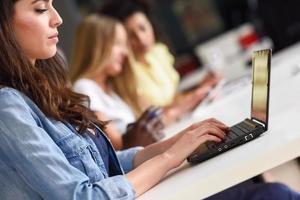 mujer joven que estudia con la computadora portátil en el escritorio blanco. foto