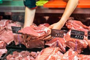 Closeup of butcher's hands holding meat piece in shop photo