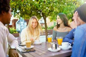 Multi-ethnic group of friends having a drink together in an outdoor bar. photo