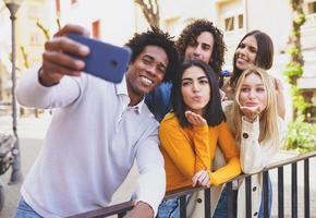 Multi-ethnic group of friends taking a selfie in the street with a smartphone.