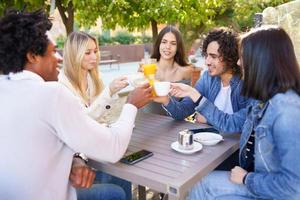 grupo multiétnico de amigos brindando con sus bebidas mientras toman una copa juntos. foto