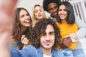 Grupo multiétnico de amigos tomando un selfie juntos mientras se divierten al aire libre. foto