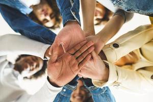 manos de un grupo multiétnico de amigos se unieron como muestra de apoyo y trabajo en equipo. foto