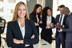 Líder empresaria en la oficina moderna con empresarios que trabajan en segundo plano. foto