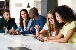 Grupo multiétnico de jóvenes que estudian con ordenador portátil foto