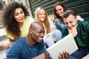 grupo multiétnico de jóvenes mirando una tableta foto