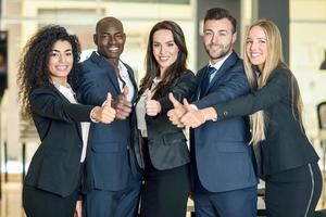 Group of businesspeople with thumbs up gesture in modern office. photo