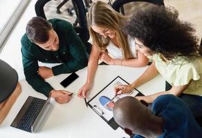 Grupo multiétnico de jóvenes que estudian con ordenador portátil foto