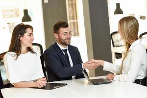 Smiling young couple shaking hands with an insurance agent photo