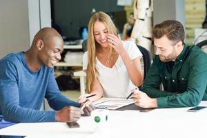 Multi-ethnic group of three young people studying and smiling together photo