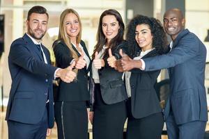 Group of businesspeople with thumbs up gesture in modern office. photo