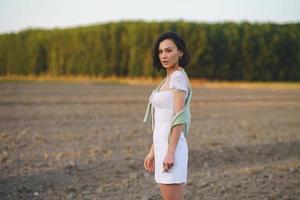 Asian woman, walking in the countryside, wearing a white dress. photo