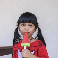 An Asian little girl is happily eating ice cream. photo