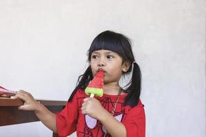 An Asian little girl is happily eating ice cream. photo