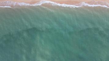 bovenaanzicht, blauwe oceaangolven raken zachtjes het strand. op een zonnige dag. video