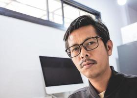 un retrato de un joven asiático sentado en su escritorio con una computadora. foto