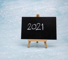 The message 2021 is written in white chalk on a black chalk board. photo