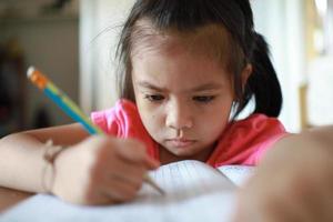 A cute Asian girl doing homework in her home during the day photo