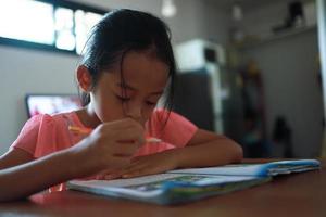 A cute Asian girl doing homework in her home during the day photo