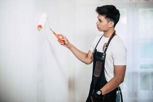 A carpenter holds a paintbrush and paints wood. photo