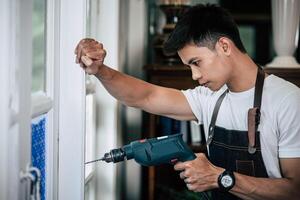 The carpenter holds the drill and drills the window. photo